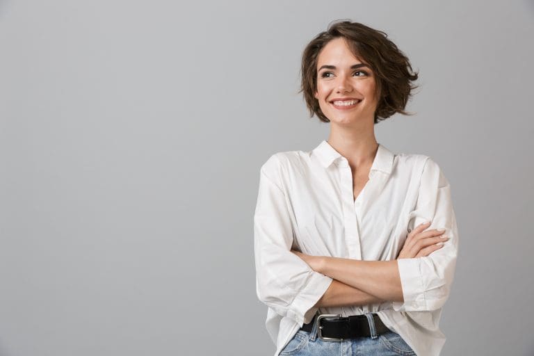 Happy young business woman posing isolated over grey wall background.