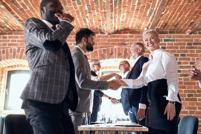 Colleagues smile shake hands in honor of successfully closed deal