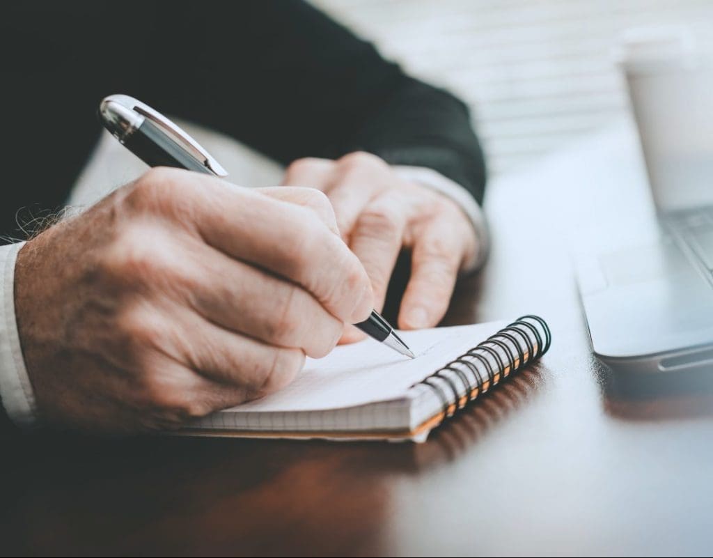 Hands taking notes on notebook; panoramic banner