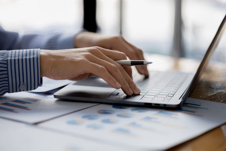 A business man is checking company financial documents and using