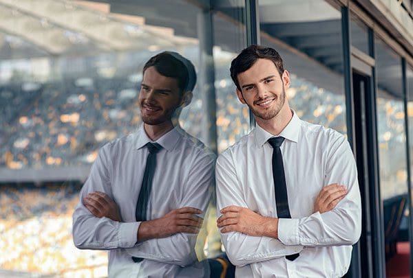 Portrait of young man dressed in business suit standing near stadium office