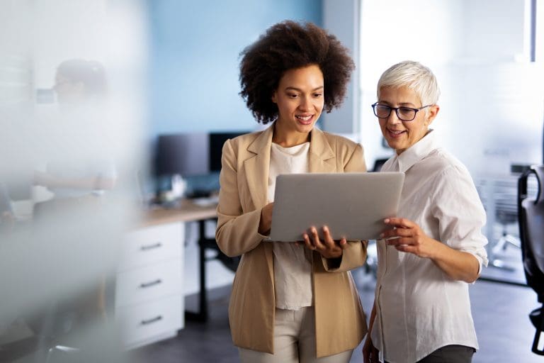 Happy smiling business women working together online on a laptop in office