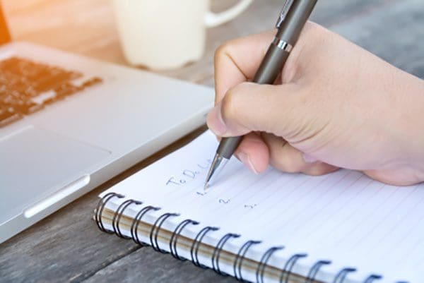 Close up of someone writing a list in a notebook