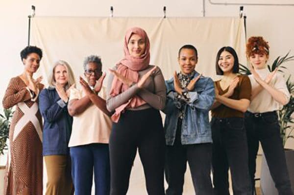 Middle Eastern woman wearing hajib gesturing Break The Bias in support of International Women's Day with female friends