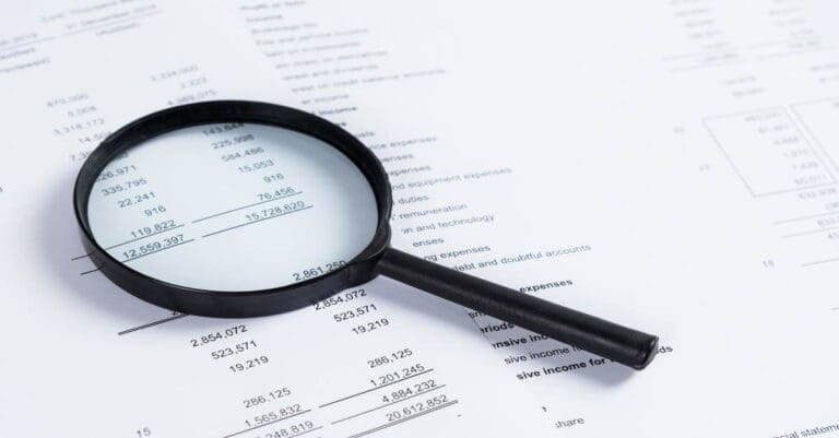 Magnifying glass on financial statement paper. Analyzing business financial data.
