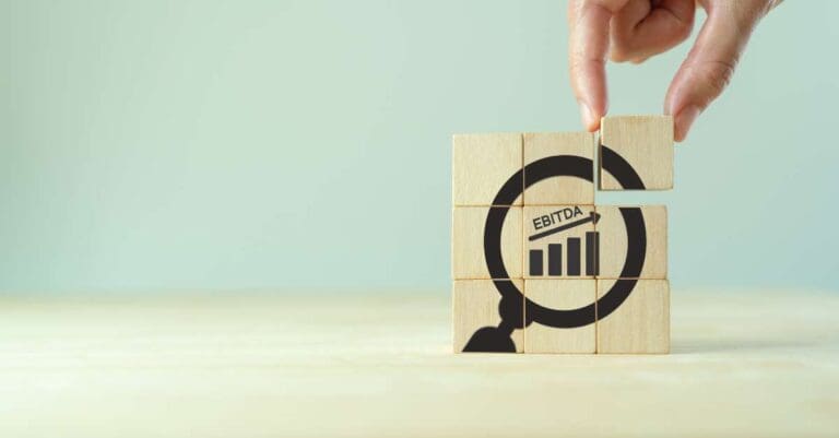 EBITDA Earnings Before Interest, Taxes, Depreciation and Amortization. Business, financial, money investment profit concept. Hand placed wooden cube with focused"EBITDA" text and increasing graph.