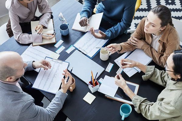 Smiling female leader, coach holding briefing for multiracial team interns in office, teaching students, plan to subordinates. Businesswoman at company meeting with diverse colleagues.